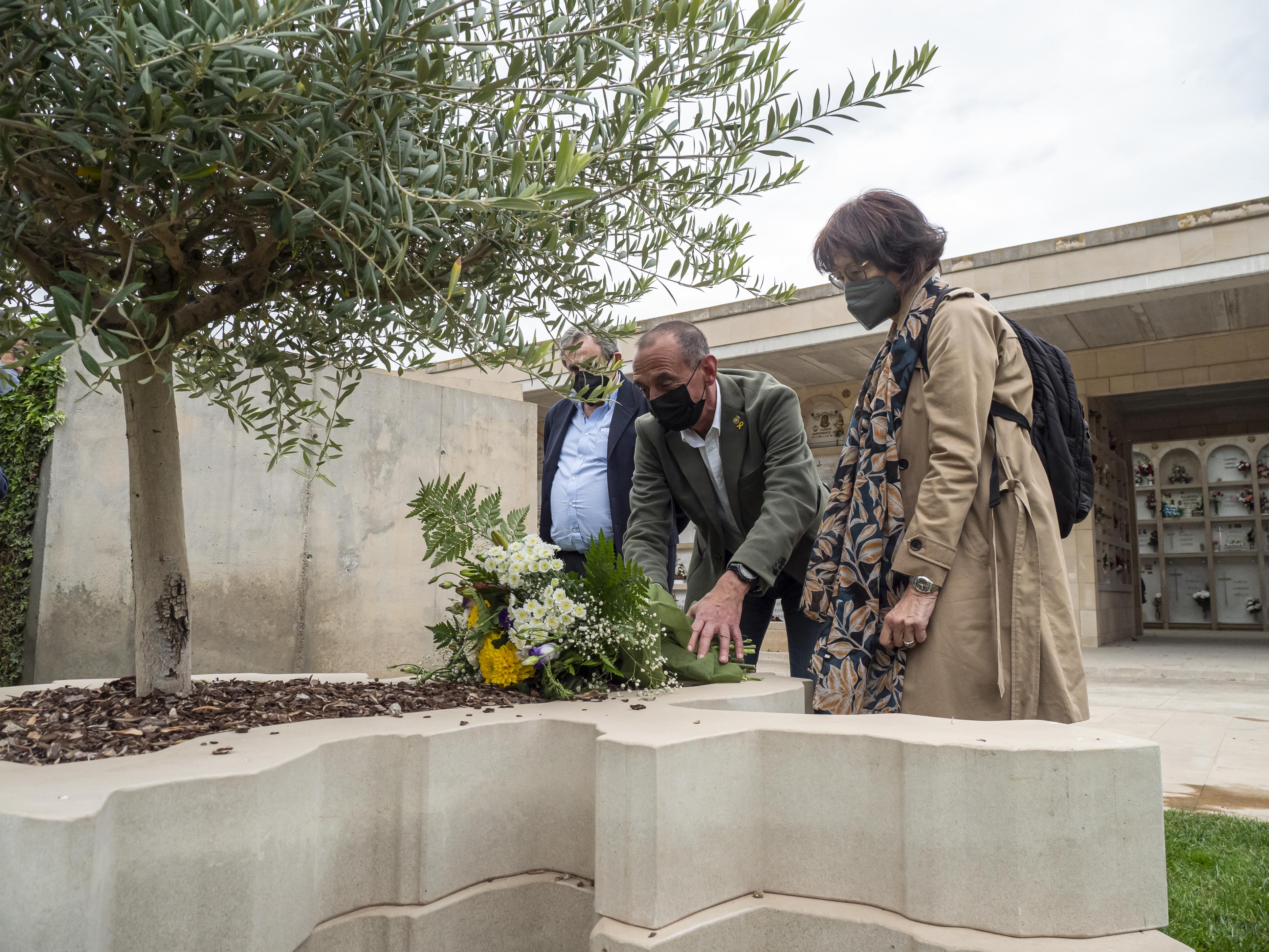 Dipositan un dels rams de flors en l'escultura en record de les víctimes de la pandèmia