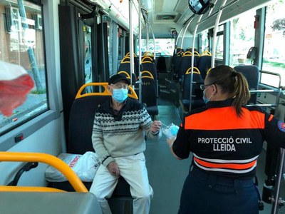 Una voluntària de Protecció Civil oferint una mascareta a un usuari de l'autobús urbà.