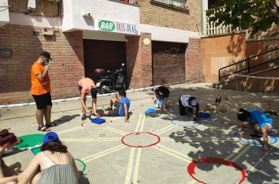 Joves de la Mariola pinten jocs tradicionals en una plaça del barri.