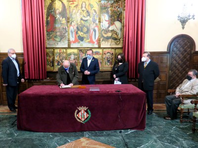 Toni Baró signa el conveni sota la mirada de Miquel Pueyo, al Saló del Retaule.