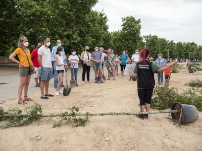 Una educadora ambiental explica a les famílies com fer la plantació.