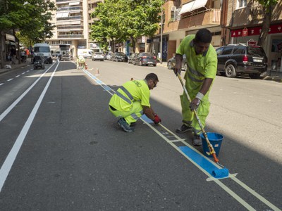 Dos operaris repinten senyalització a l'avinguda de València, en el marc de les obres..