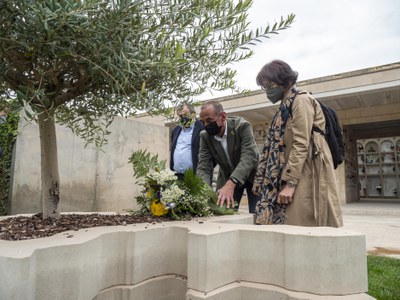 Dipositan un dels rams de flors en l'escultura en record de les víctimes de la pandèmia.