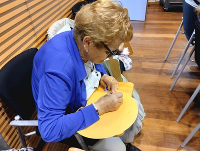 Una de les assistents participa en el mural aportant la seva visió sobre la soledat en les persones grans.