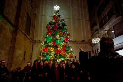 La coral Veus.kat ha fet una cantada de nadales davant el gran avet natural que decora la plaça Paeria.