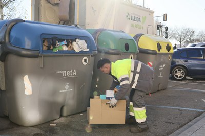 Un operario del nuevo servicio de refuerzo recoge el cartón acumulado frente a un contenedor.